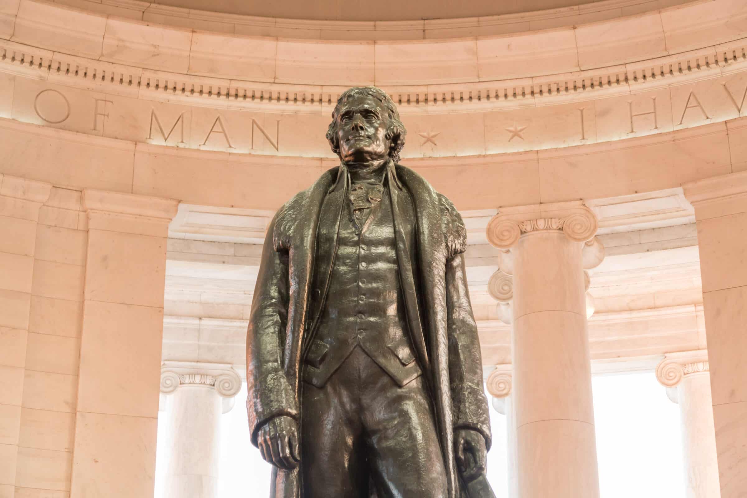 Bronze statue of Thomas Jefferson in Jefferson Memorial in Washington DC as setting sun illuminates interior of the monument