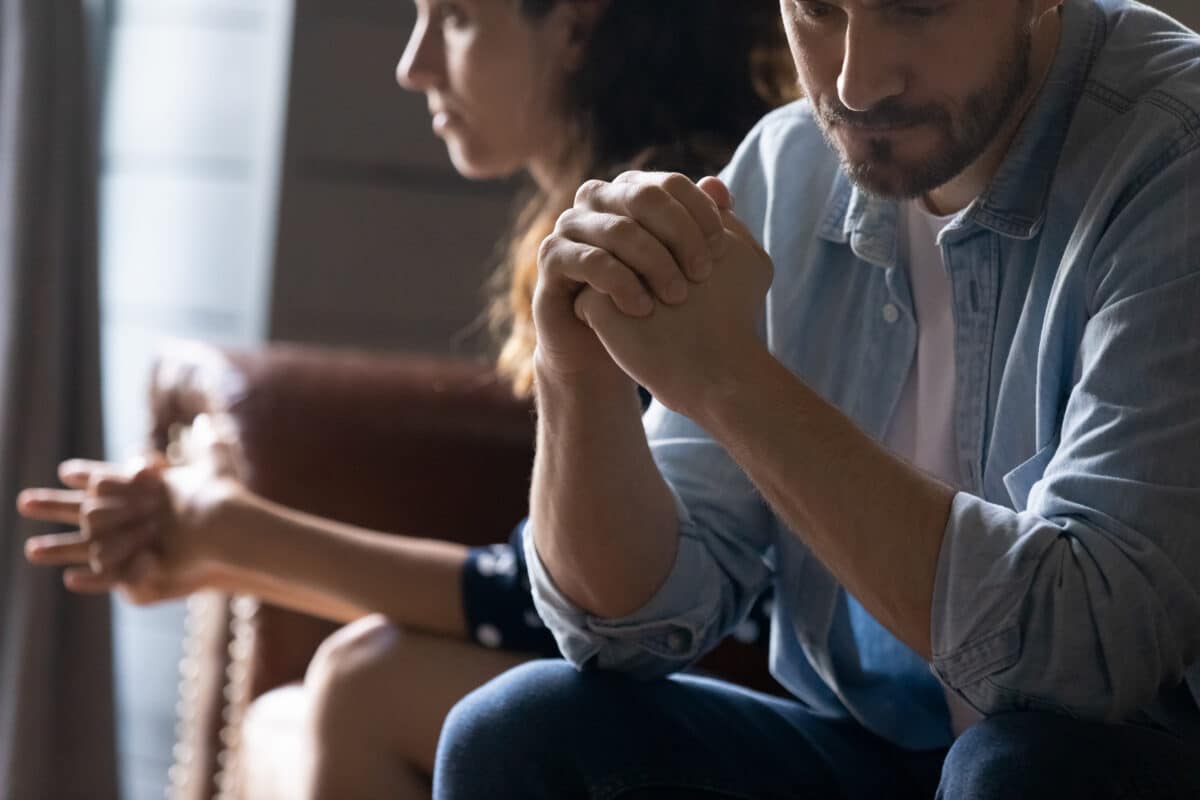 Crop close up of unhappy young couple sit separate have problems in relationship think of breakup or divorce. Upset man and woman family lovers avoid talking suffer from cheating in relation troubles.