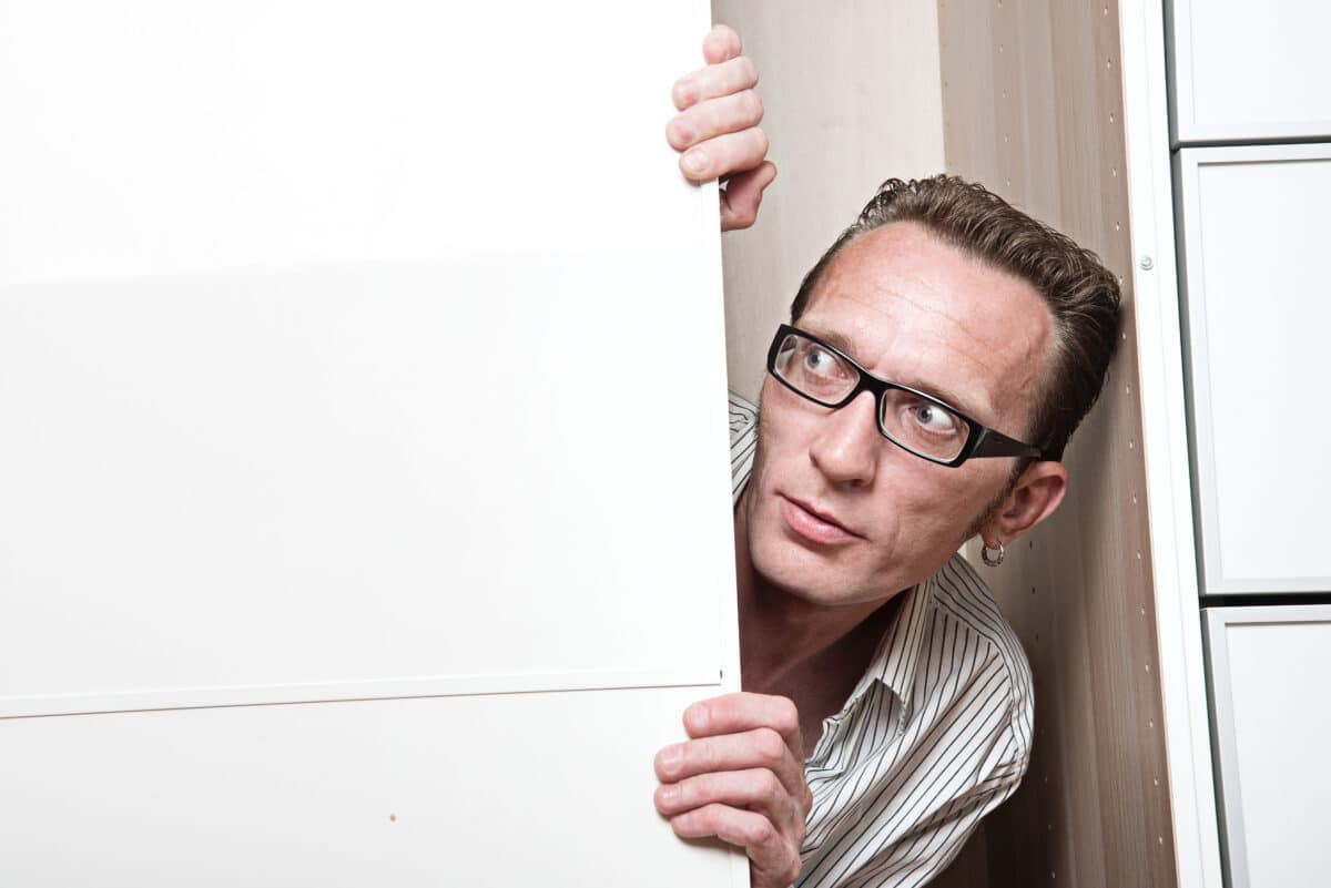 Surprised man inside white wardrobe Copy space left