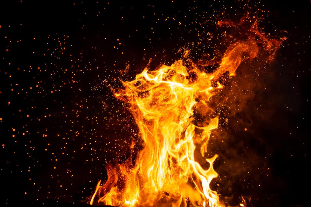Burning woods with firesparks, flame and smoke. Strange weird odd elemental fiery figures on black background. Coal and ash. Abstract shapes at night. Bonfire outdoor on nature. Strenght of element.