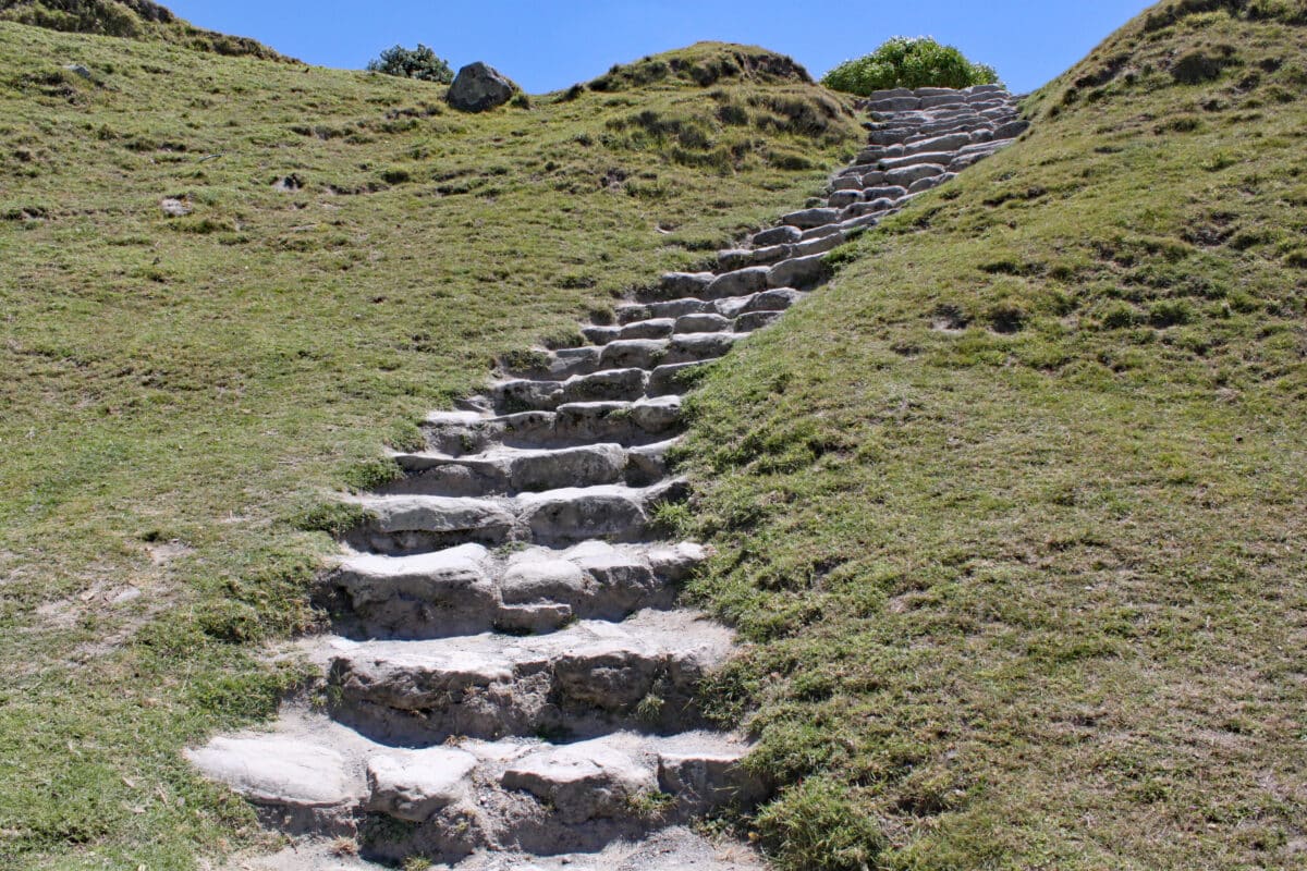 Stone steps cut into a grassy bank lead up the hillside to the summit.