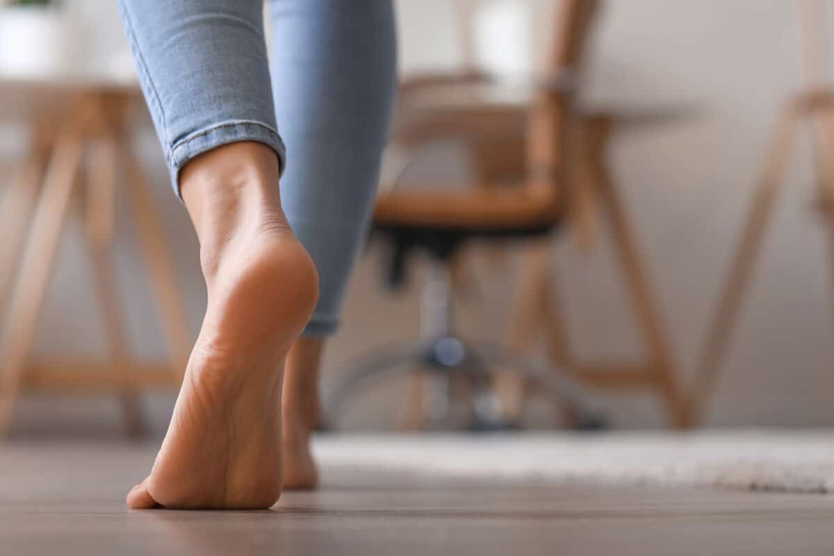 Bare foot of young woman walking at home, closeup