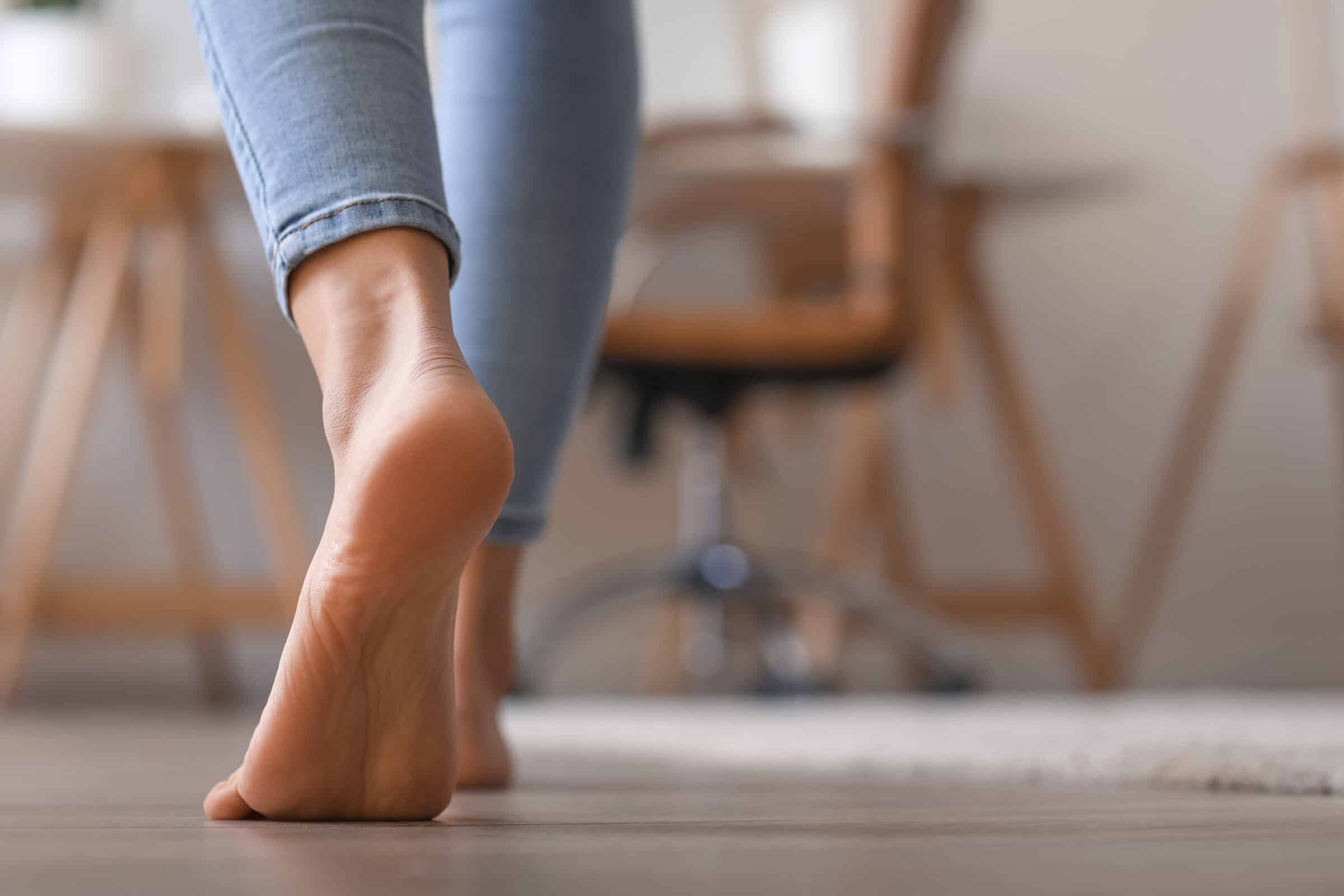 Bare foot of young woman walking at home, closeup