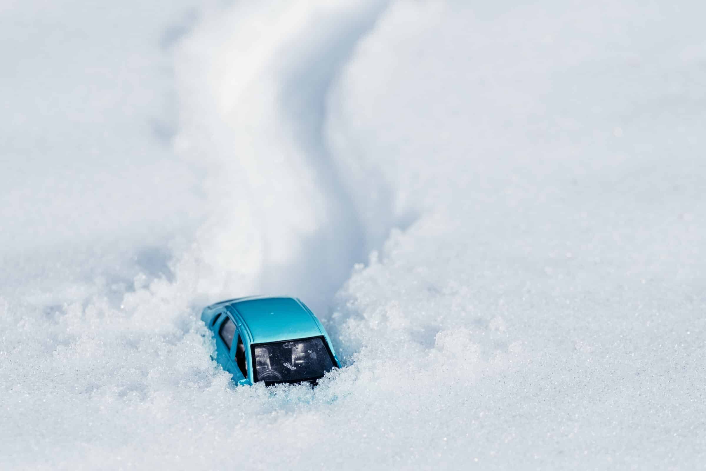 footprints and a car in the snow, a car stuck in a large pile of snow