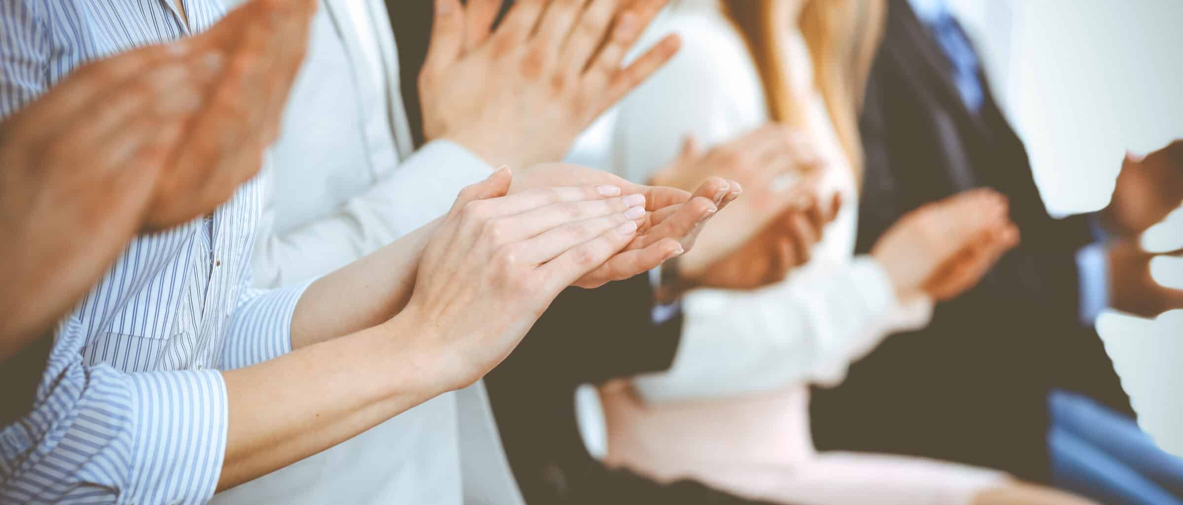 Business people clapping and applause at meeting or conference, close-up of hands. Group of unknown businessmen and women in modern white office. Success teamwork or corporate coaching concept