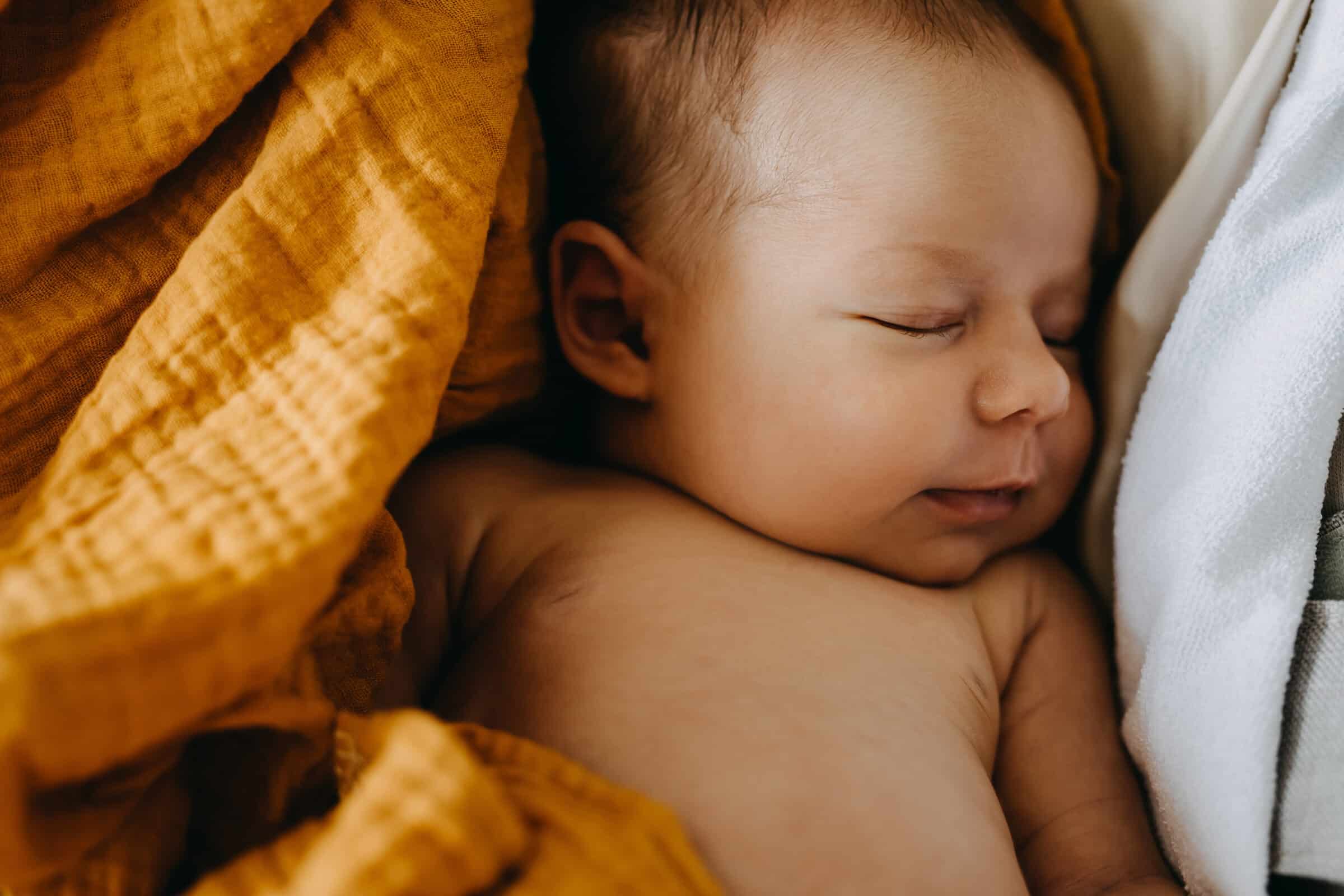 Closeup of a newborn baby dreaming and smiling while sleeping.
